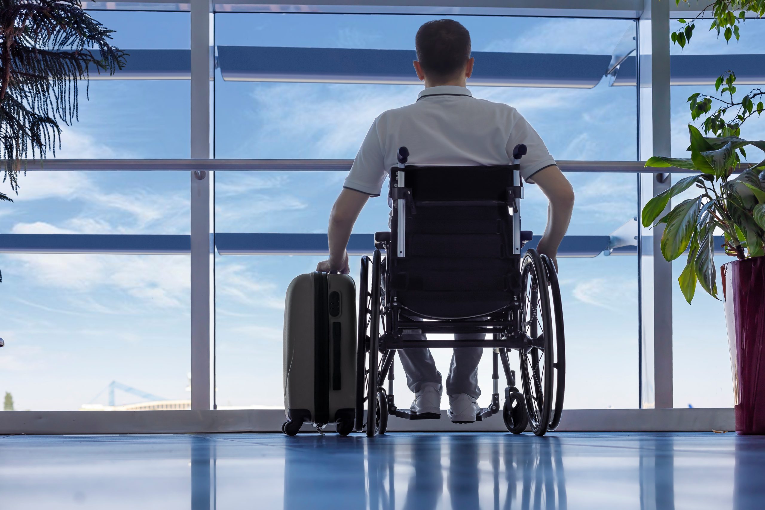 Young man in a wheelchair at the airport Young man in a wheelchair with luggage at the airport closeup